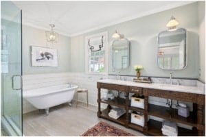 A bright bathroom with a tub and wood vanity