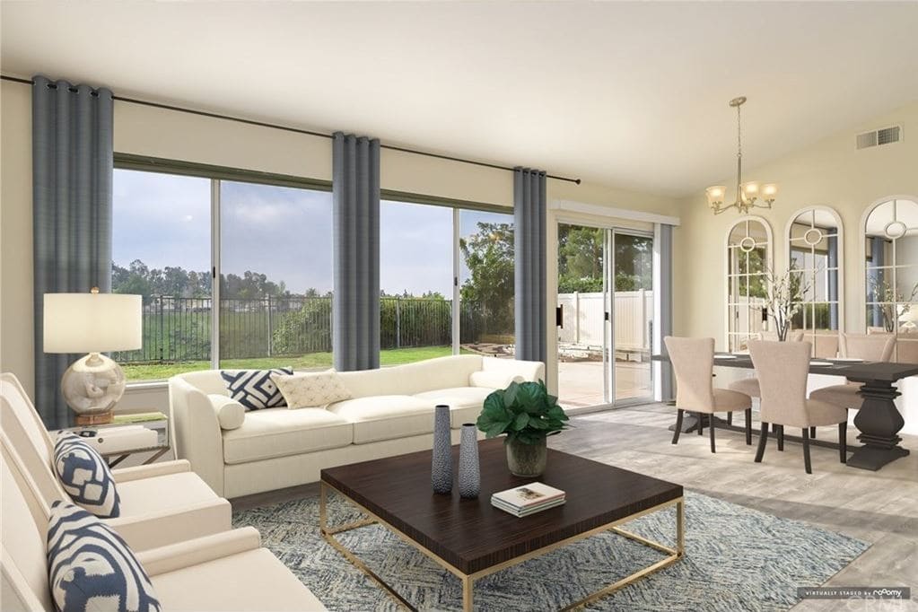 Living room with couch, coffee table, and windows opening up to the backyard