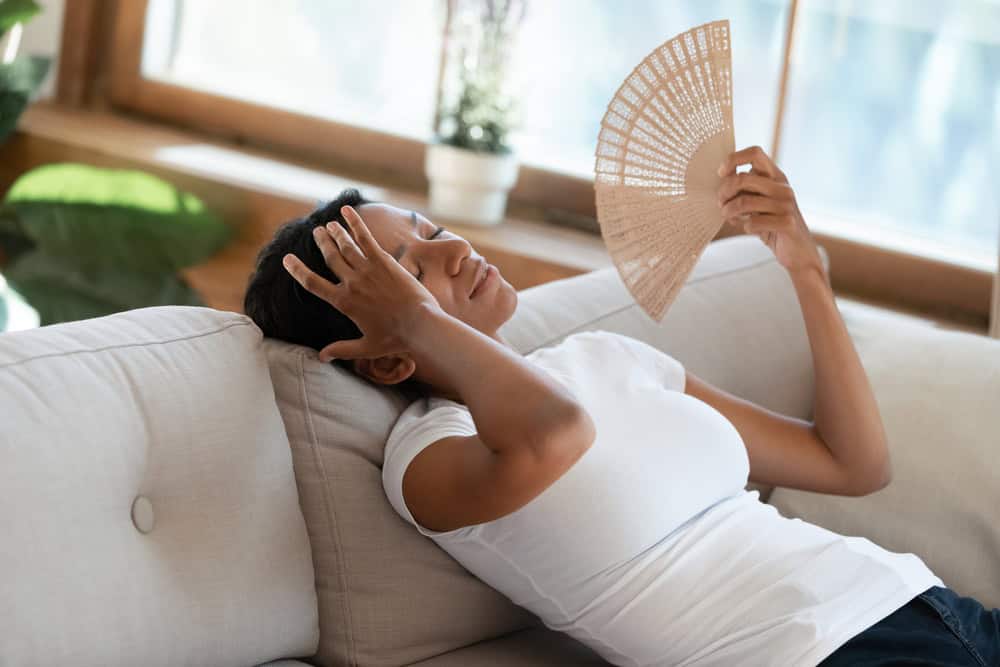 A woman indoors fanning herself from the heat