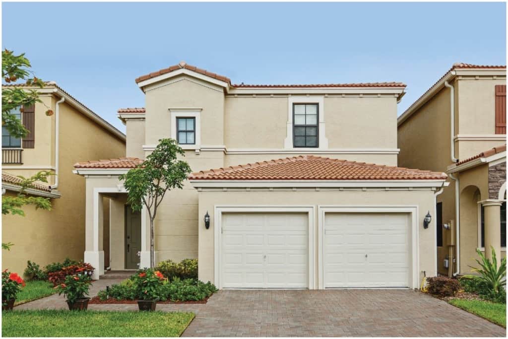 A tan colored house with a palm tree in the front