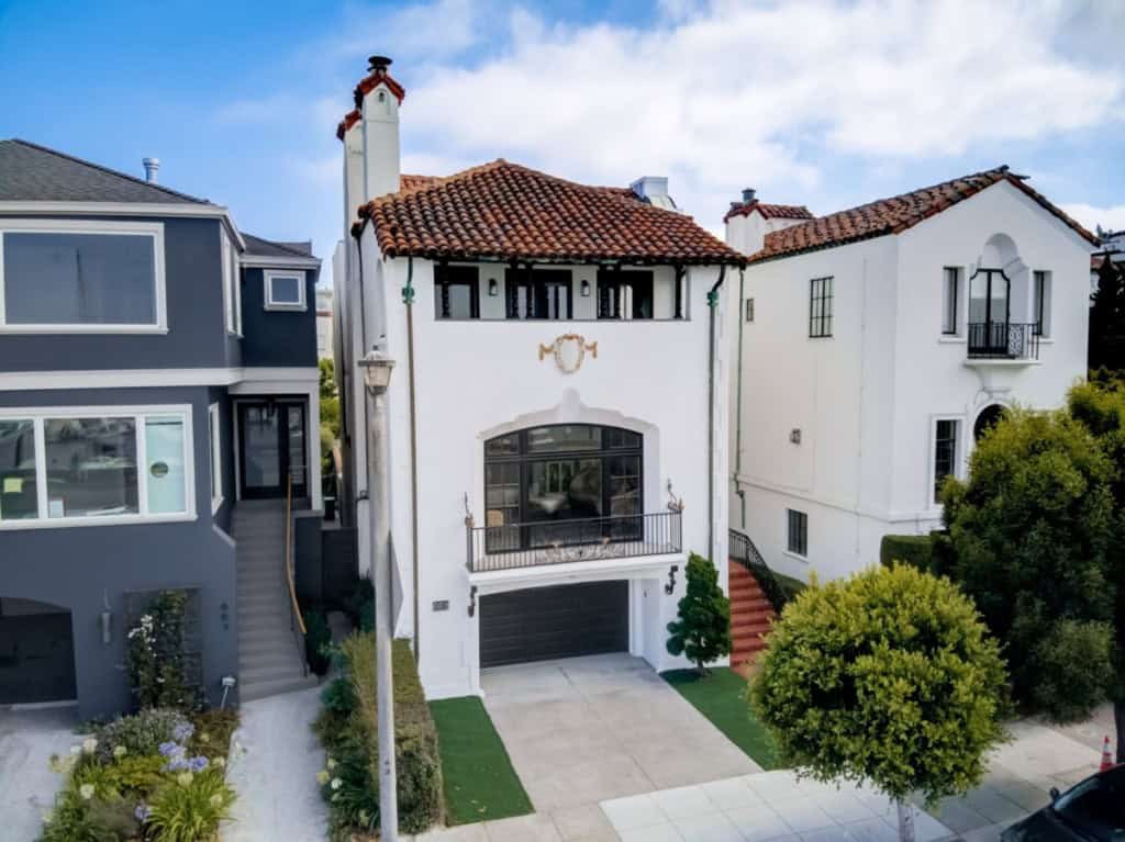houses close together, white with brown roof and trimmed trees