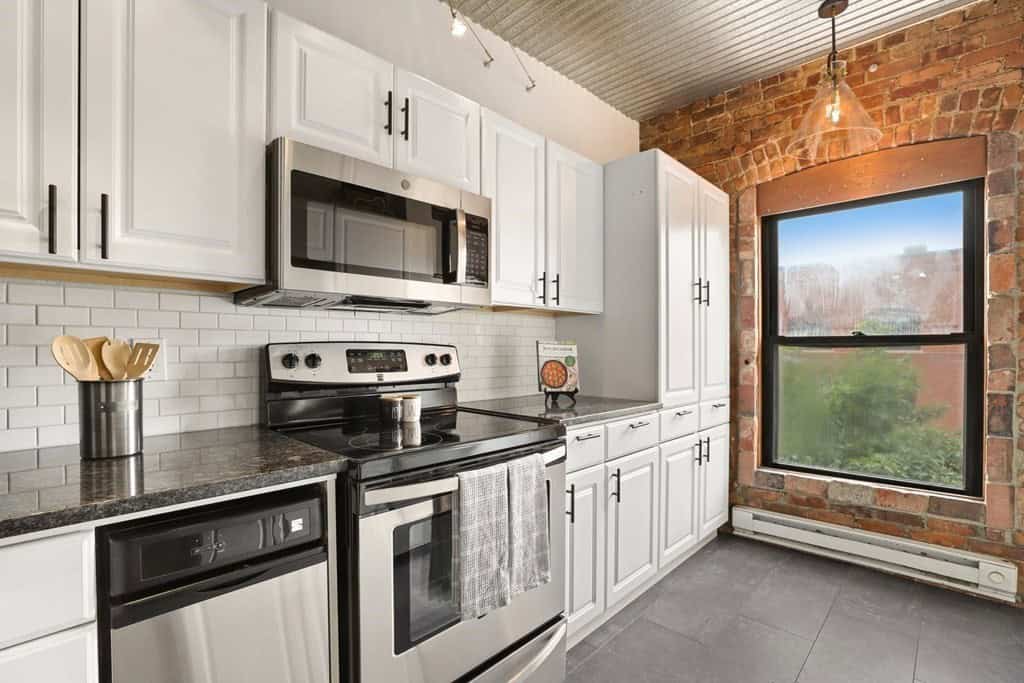 one wall kitchen with a couple appliances and white cabinets