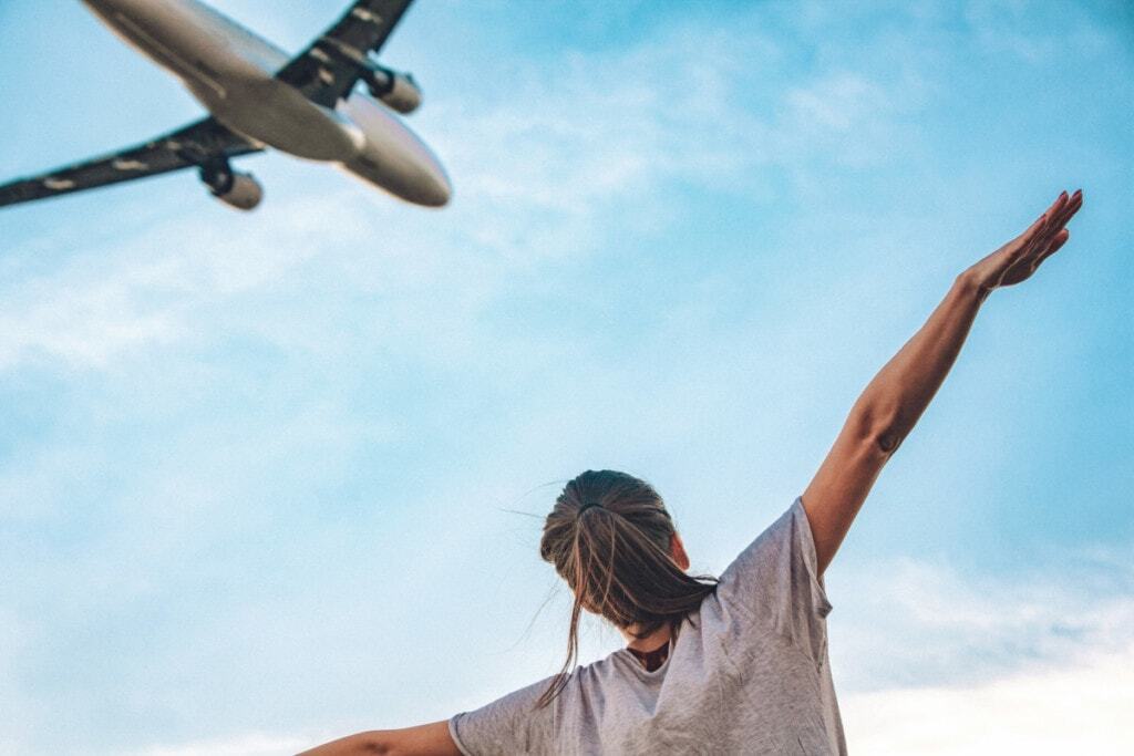 An airplane flying over a woman with her arms reached out