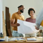 couple talking to real estate agent in the apartment. while holding plans