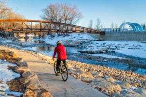 Man in a winter coat biking on an urban trail in Fort Collins, CO