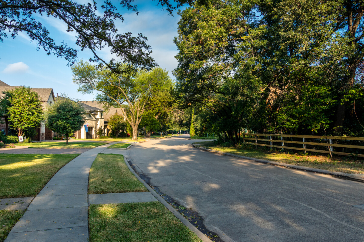 Quiet,Neighborhood,Street,With,Trees,And,Fence,On,Summer,Morning