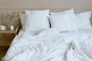 A bed made with cooling sheets for hot sleepers, featuring a light duvet and minimalist decor, conveying a fresh and airy feel.