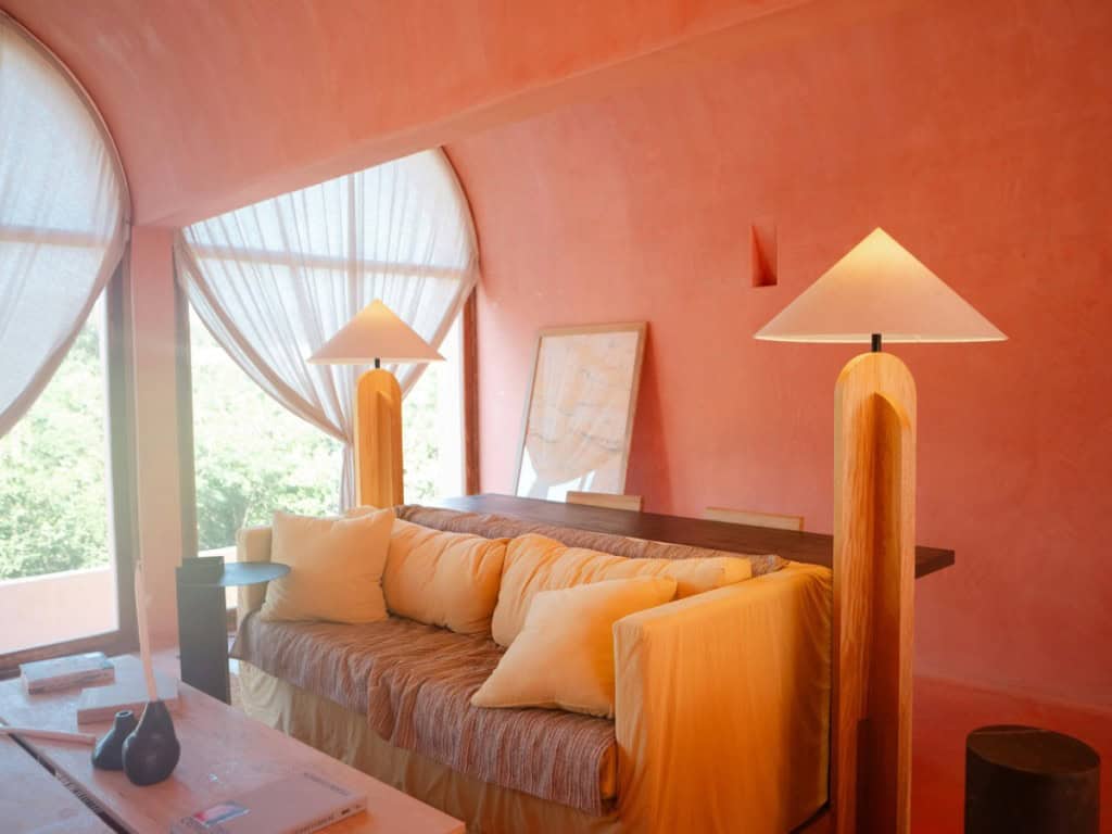 a pink color-washed room lit by two distinct, modern lamps