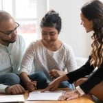A young couple looks over legal documents after selling their house