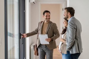 Real estate agent guiding a couple through a home, discussing their house hunting checklist