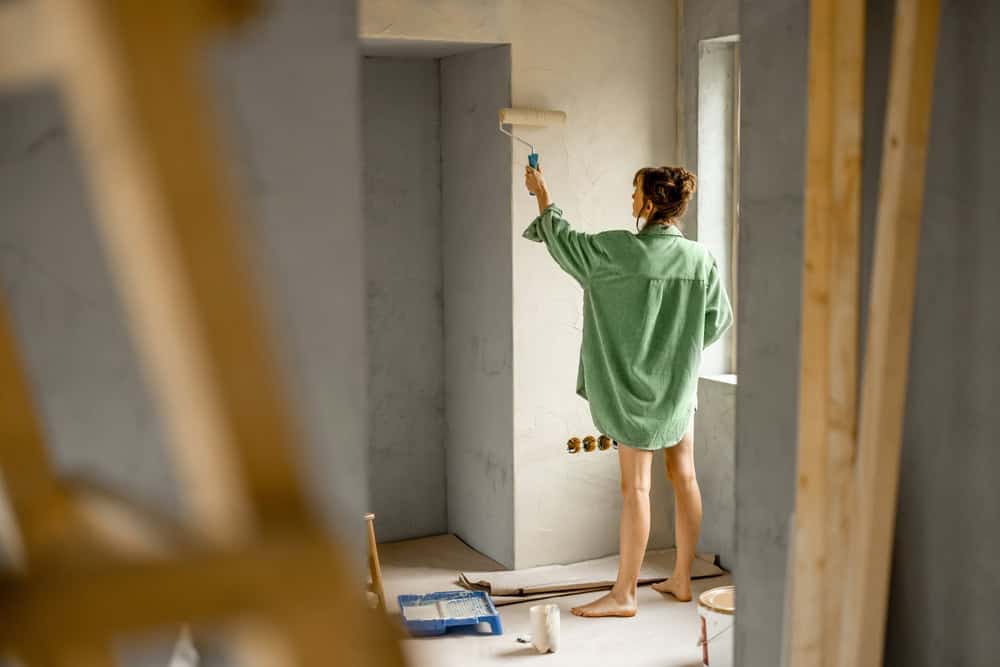 Woman paints a wall in preparation of selling her home