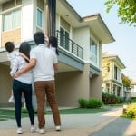A family of four looks up at the new house they are buying in another state.