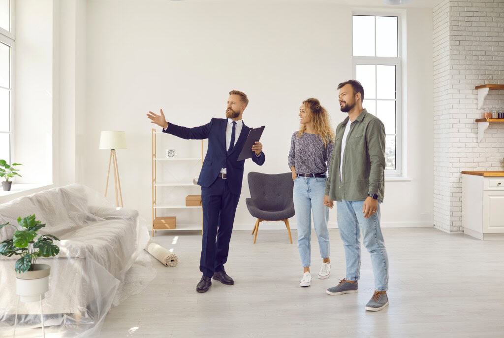 Couple attending a house viewing led by a realtor discussing the layout.