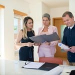 People standing around looking at documents illustrating how to negotiate on house price