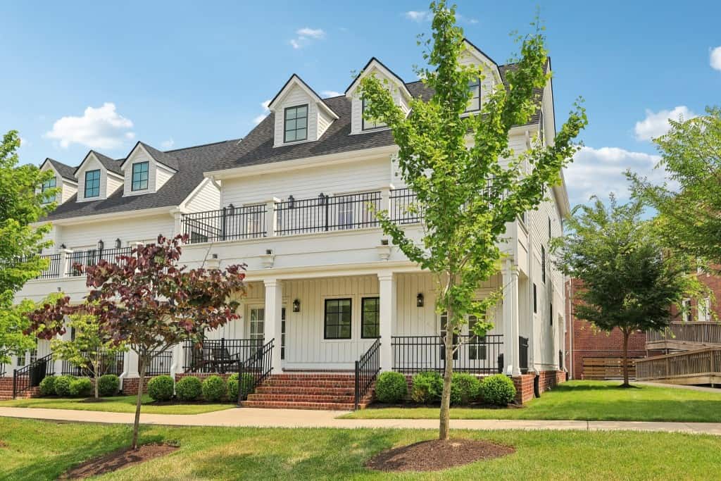 beautiful white home with brick steps manicured front lawn
