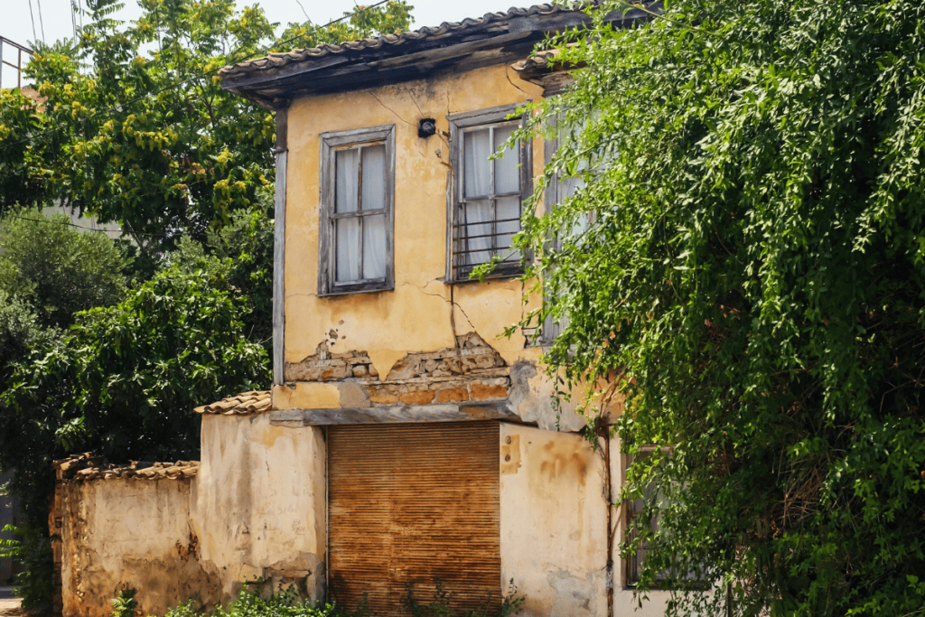 Old, rundown yellow house with visible cracks and damage, a good example for how to sell a teardown house.