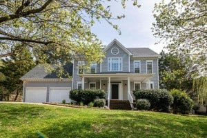 Two-story suburban home with a front porch, garage, and landscaped yard—example used in guide on how to find market properties