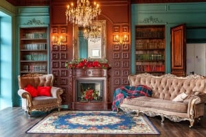A vintage, Victorian-era living room color-bathed in a rich teal paint. Ornate bookshelves line the walls and cushy vintage seating completes the look.