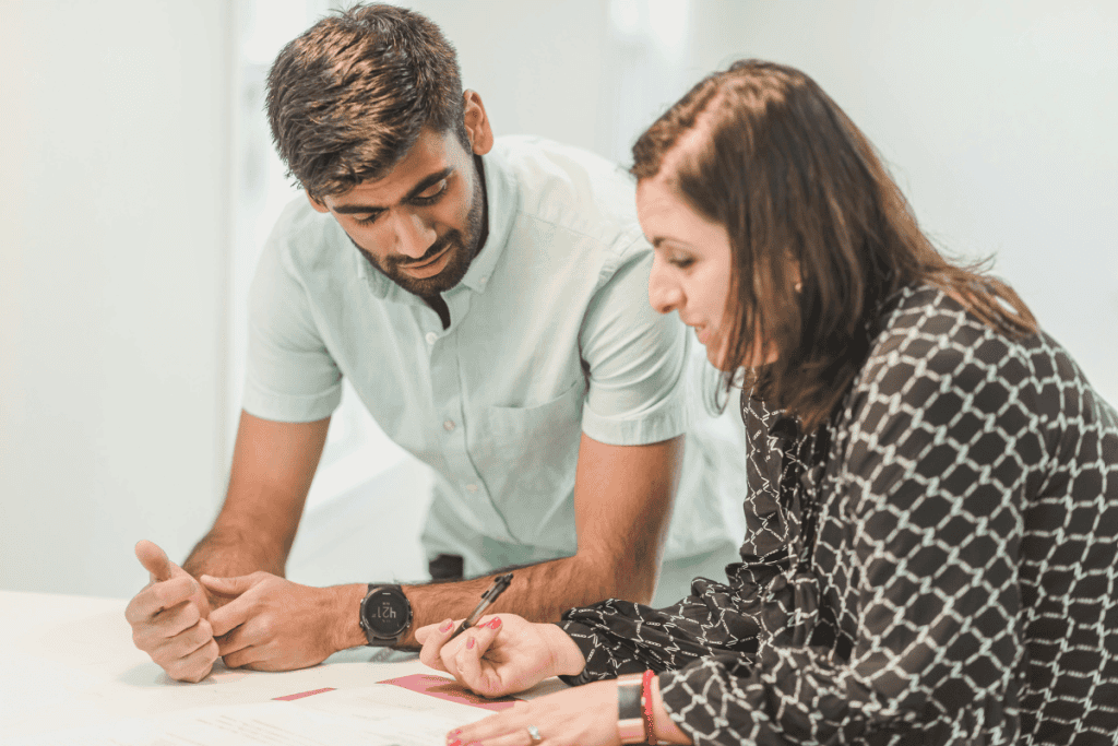 Two people reviewing paperwork at a table, discussing details related to Earnest Money vs. Option Fee during a home-buying process.