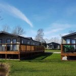 A modern manufactured or mobile home in a sunny and lush community.