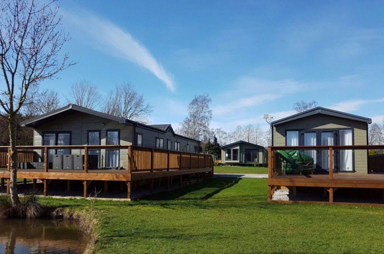 A modern manufactured or mobile home in a sunny and lush community.