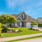 A large, new home in a grassy suburban neighborhood.