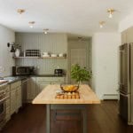 A modern kitchen with soft green paint and warm wood tones, complemented by brass lighting. An updated kitchen is one of the top reasons a home might appraise higher.