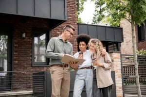 A young couple looks over an inspection report in front of a modern brick home