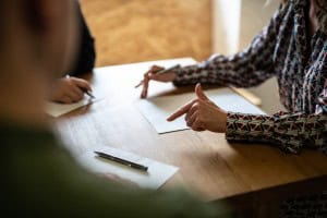 Three people sit around a table with partition action documents on it. One person is a partition lawyer who is explaining the documents to the other two people.