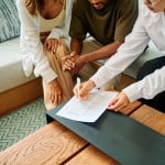A couple going over the final closing paperwork with their agent before buying a home