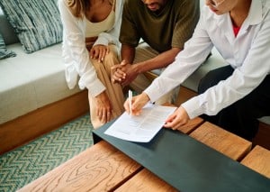 A couple going over the final closing paperwork with their agent before buying a home