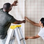 Two people are working on putting up wallpaper.