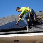 man installing solar panel on a roof