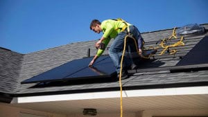 man installing solar panel on a roof