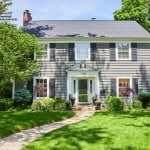 A two-story house with a pathway cutting through the grass leading up to the front door. A seller might want to know what it would be like selling this home to an iBuyer.