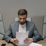 man reading paper siting at table