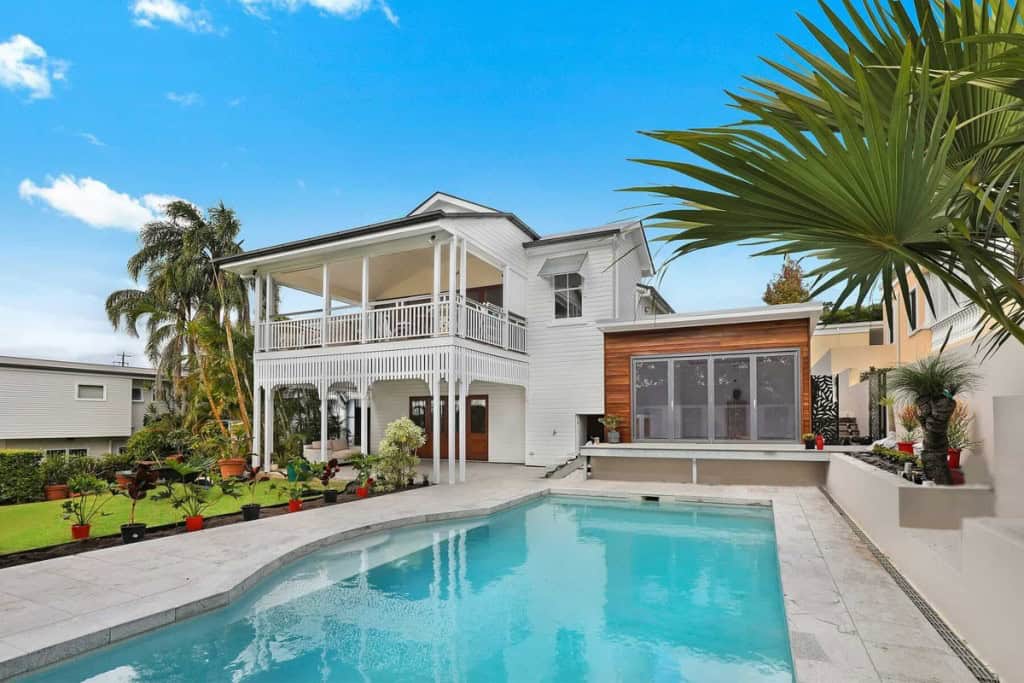 A white two-story house with a swimming pool, illustrating what happens to your mortgage when you sell your house.