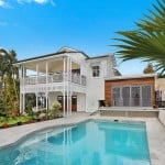 A white two-story house with a swimming pool, illustrating what happens to your mortgage when you sell your house.